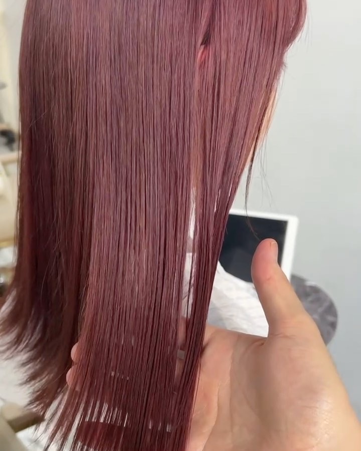 手で広げたワインレッドのストレートヘアのクローズアップ。